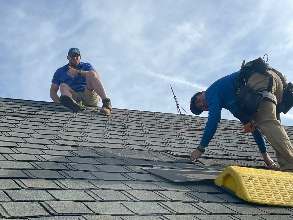 Roof repair technicians inspecting and repairing asphalt shingles.
